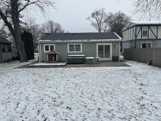 snow covered property featuring a patio area and a hot tub