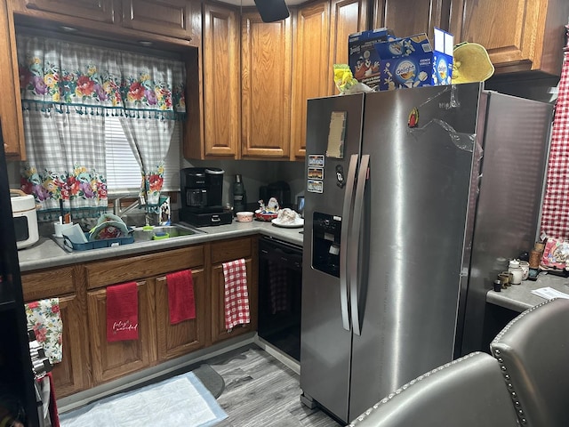 kitchen featuring light wood-type flooring, stainless steel fridge with ice dispenser, and black dishwasher