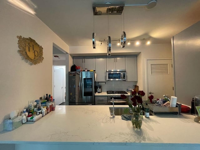 kitchen with gray cabinets, stainless steel appliances, and tasteful backsplash