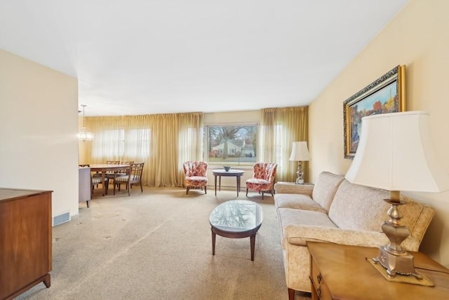 carpeted living room featuring a notable chandelier