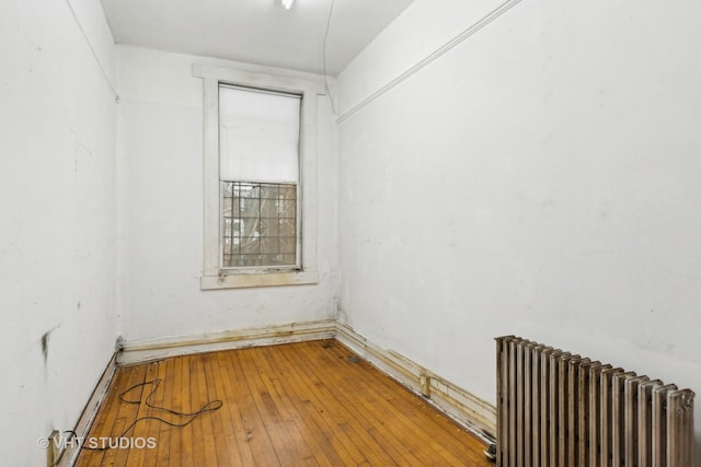 empty room featuring radiator heating unit and hardwood / wood-style floors