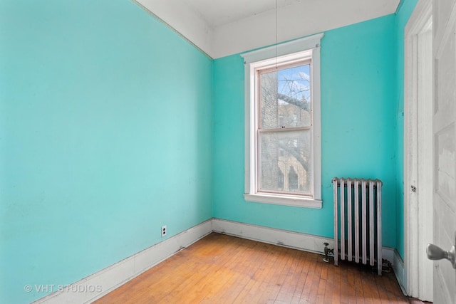 empty room with hardwood / wood-style floors and radiator heating unit