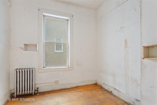 empty room with radiator and hardwood / wood-style flooring