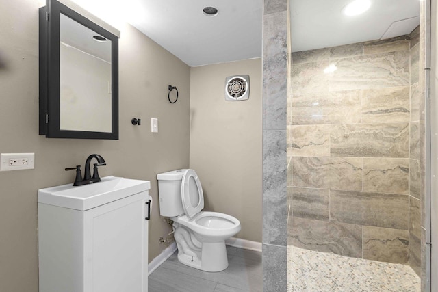 bathroom featuring a tile shower, vanity, and toilet