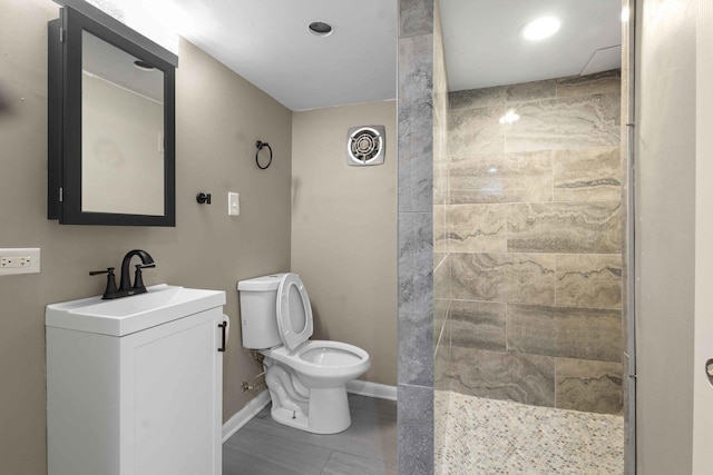 bathroom featuring vanity, toilet, and a tile shower