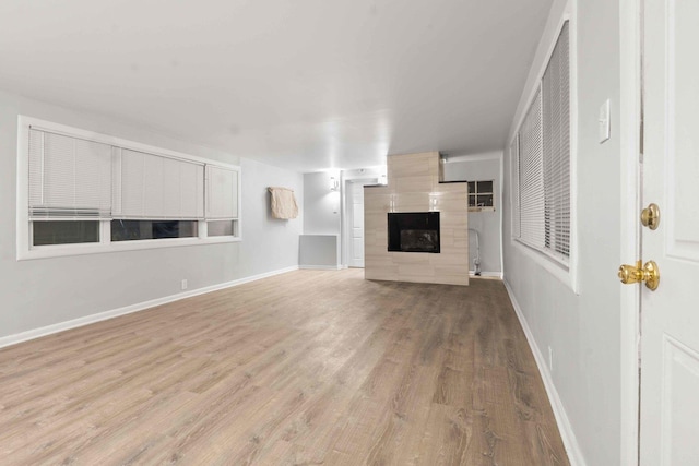 unfurnished living room with a tile fireplace and light hardwood / wood-style flooring