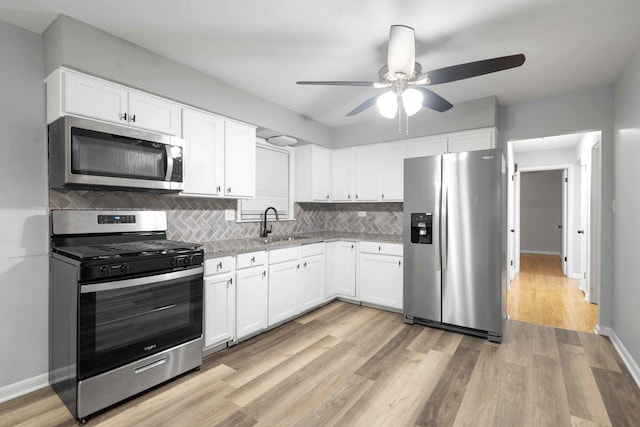 kitchen featuring white cabinets, appliances with stainless steel finishes, backsplash, and sink