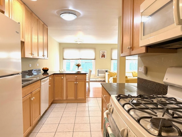 kitchen with light tile patterned floors, sink, kitchen peninsula, and white appliances