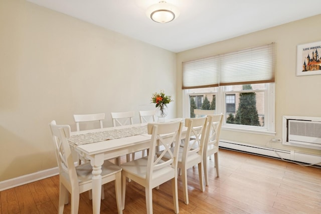 dining space with baseboard heating, an AC wall unit, and light hardwood / wood-style floors