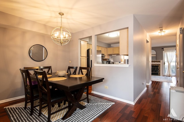 dining area with dark wood-type flooring and an inviting chandelier