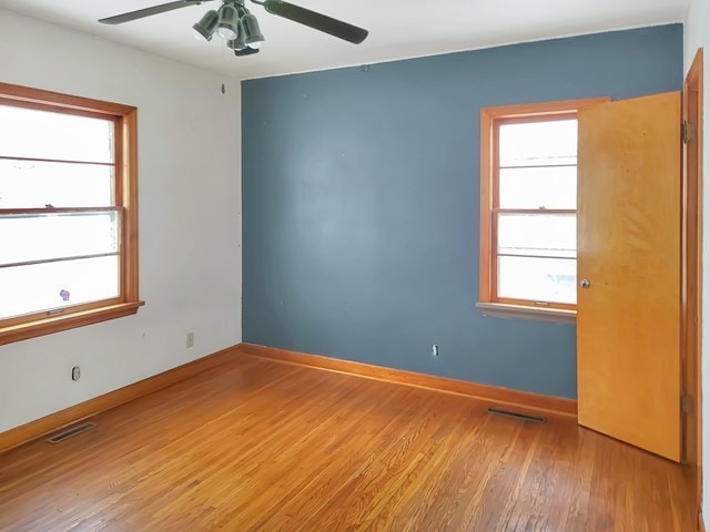 unfurnished room featuring hardwood / wood-style flooring, ceiling fan, and a healthy amount of sunlight