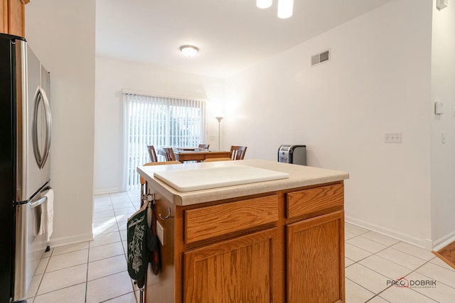 kitchen featuring light tile patterned flooring, stainless steel refrigerator, and a center island