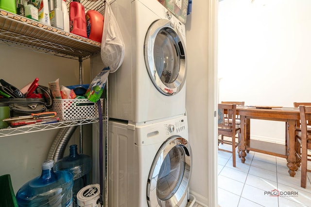 laundry room featuring stacked washing maching and dryer and light tile patterned flooring