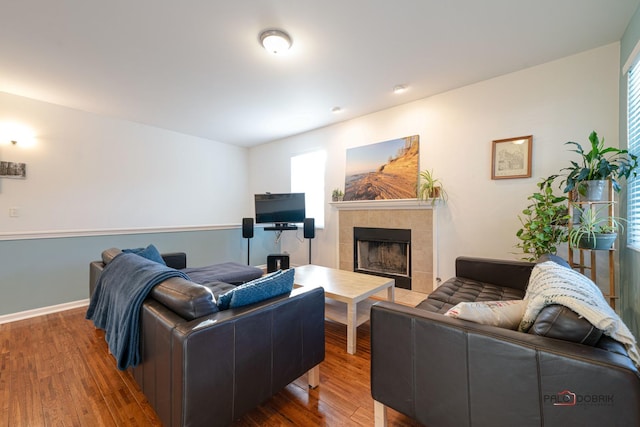 living room with a tile fireplace and hardwood / wood-style flooring