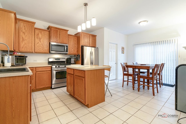 kitchen featuring appliances with stainless steel finishes, decorative light fixtures, light tile patterned flooring, a kitchen island, and sink