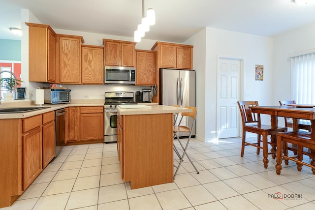 kitchen featuring light tile patterned flooring, stainless steel appliances, a kitchen island, and decorative light fixtures