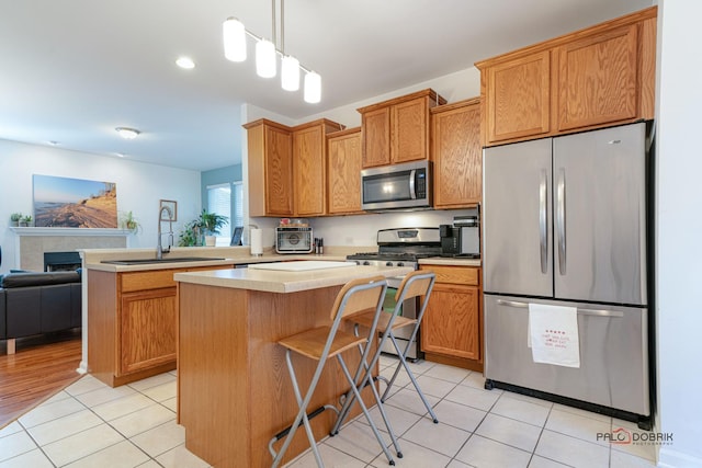 kitchen with sink, hanging light fixtures, stainless steel appliances, and a kitchen island