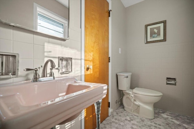 bathroom with toilet, tile walls, tile patterned floors, and sink