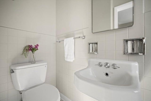 bathroom with toilet and tile walls