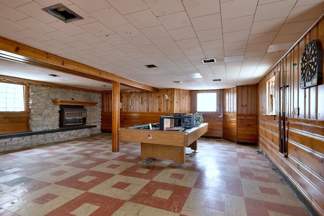 playroom with a stone fireplace and wood walls