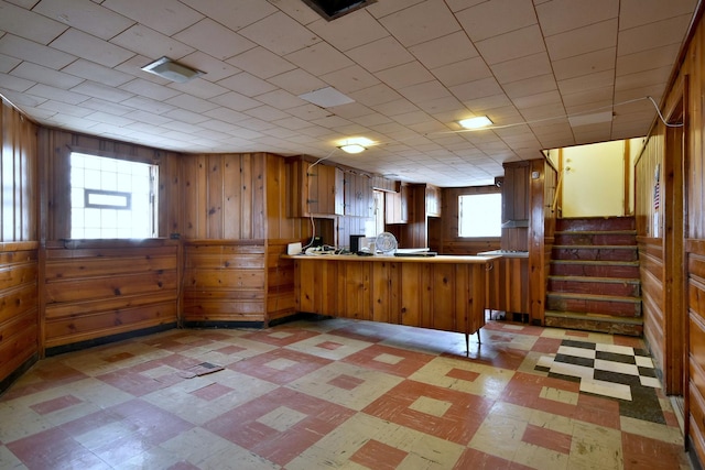 kitchen with kitchen peninsula, a wealth of natural light, and wooden walls