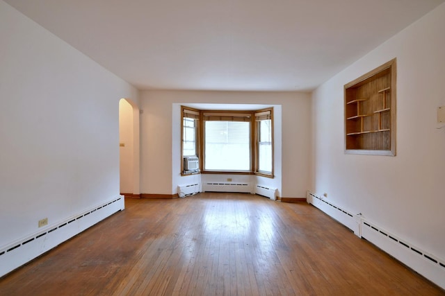 spare room with hardwood / wood-style floors, cooling unit, and a baseboard radiator