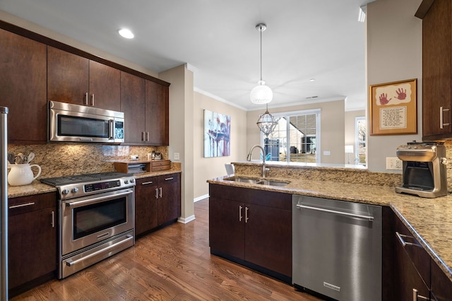 kitchen featuring pendant lighting, sink, appliances with stainless steel finishes, tasteful backsplash, and light stone countertops