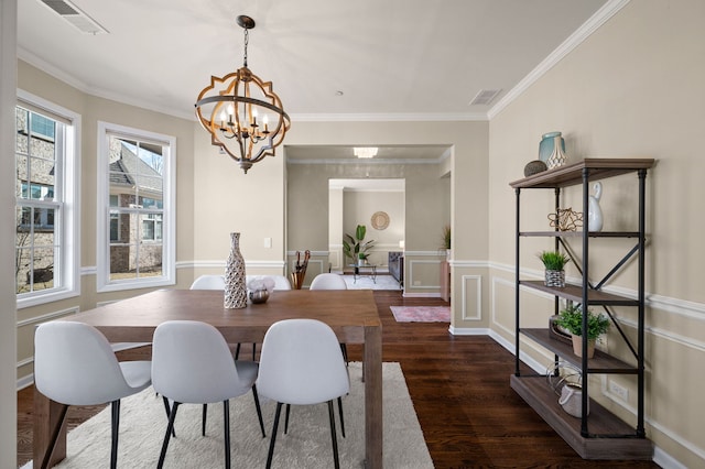 dining area featuring crown molding, dark hardwood / wood-style floors, and a chandelier