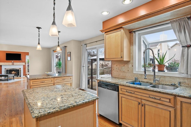 kitchen with a center island, sink, stainless steel dishwasher, pendant lighting, and a tiled fireplace