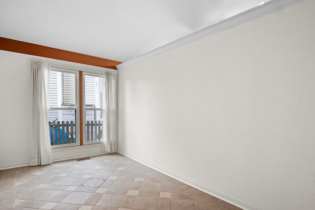 tiled spare room featuring crown molding