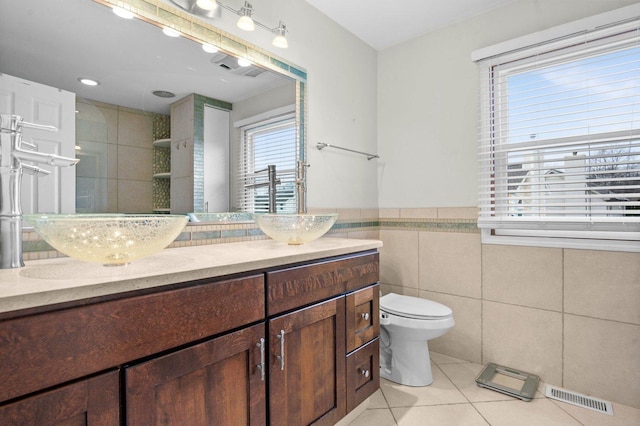 bathroom with walk in shower, tile patterned floors, toilet, vanity, and tile walls