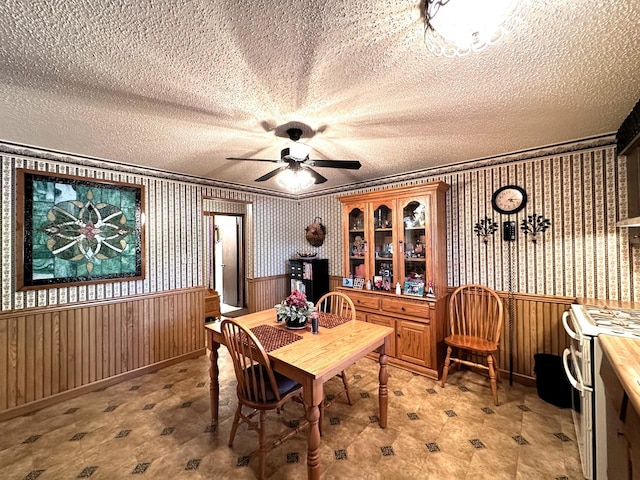 dining room featuring a textured ceiling, wooden walls, and crown molding