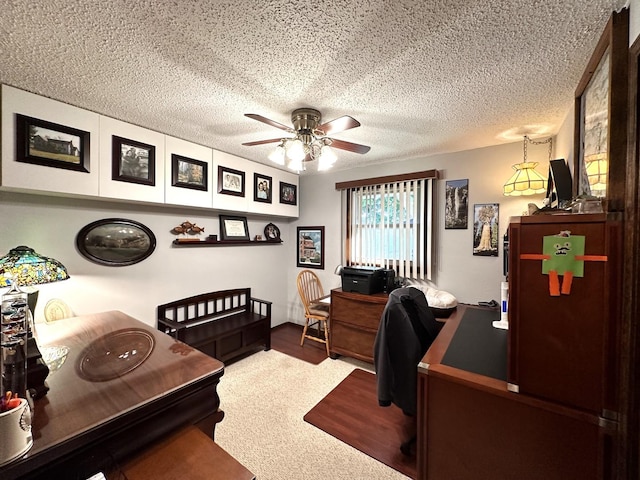 carpeted home office with ceiling fan and a textured ceiling