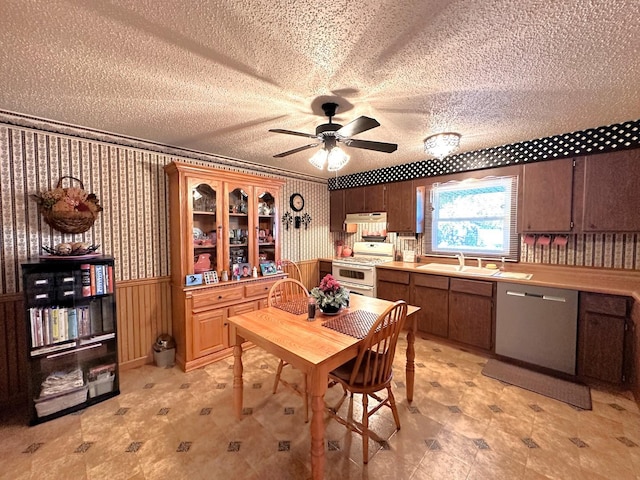 dining space with ceiling fan, wood walls, sink, and a textured ceiling