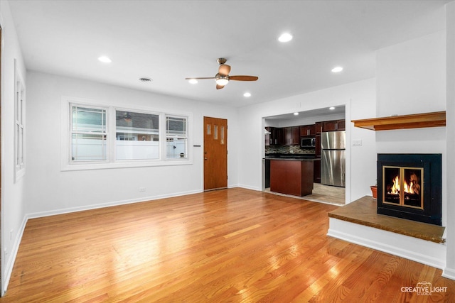 7825 N Oconto Ave, Niles, IL 60714 - unfurnished living room with a glass covered fireplace, light wood-style floors, ceiling fan, and recessed lighting
