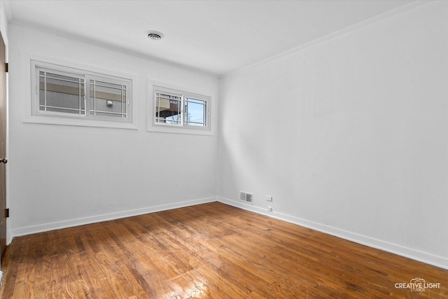 empty room featuring hardwood / wood-style flooring and ornamental molding