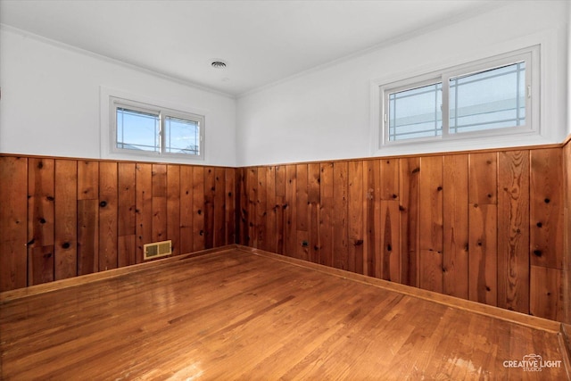 empty room featuring hardwood / wood-style floors, plenty of natural light, and wood walls