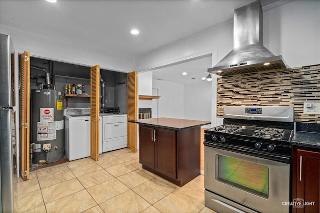 kitchen featuring gas water heater, wall chimney range hood, stainless steel gas range oven, washing machine and dryer, and a kitchen island