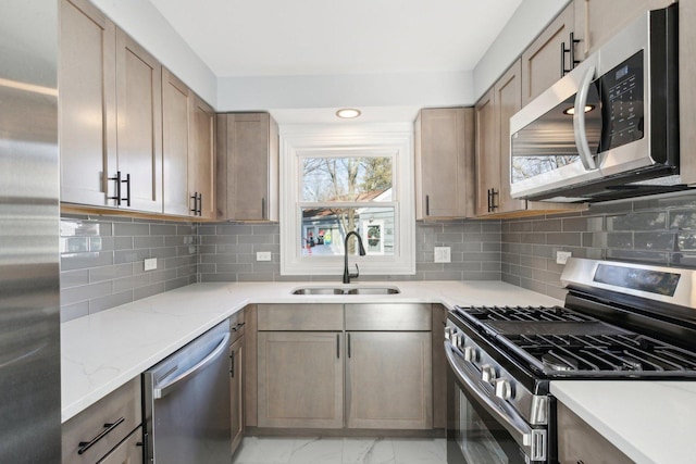 kitchen featuring decorative backsplash, sink, light stone countertops, and appliances with stainless steel finishes