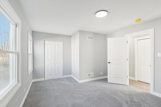 unfurnished bedroom with light colored carpet and multiple windows