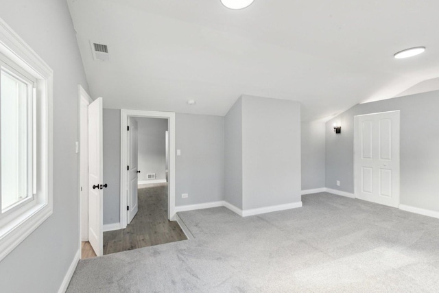 spare room with light colored carpet and vaulted ceiling