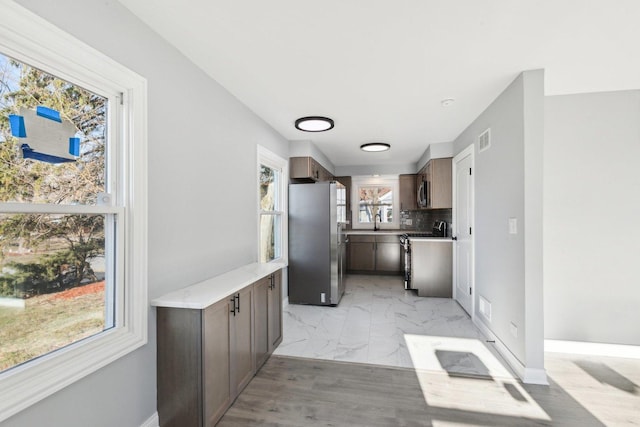 kitchen with appliances with stainless steel finishes, tasteful backsplash, a healthy amount of sunlight, and sink