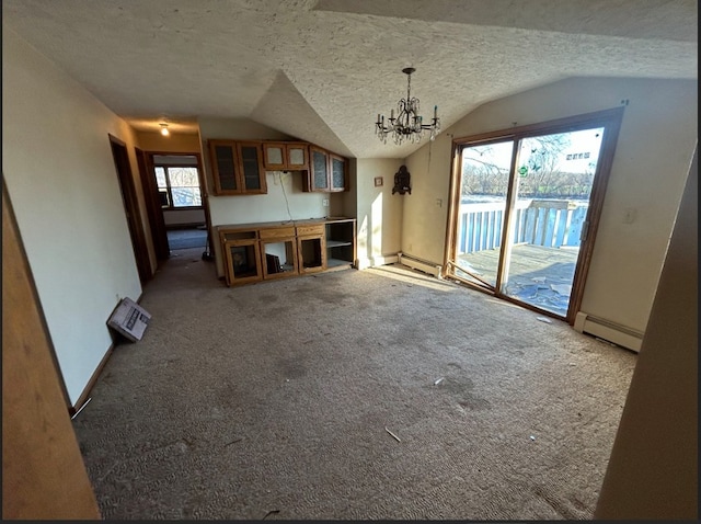 unfurnished living room featuring a textured ceiling, a healthy amount of sunlight, vaulted ceiling, and an inviting chandelier