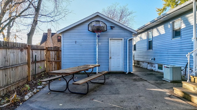 back of house with central air condition unit and an outbuilding