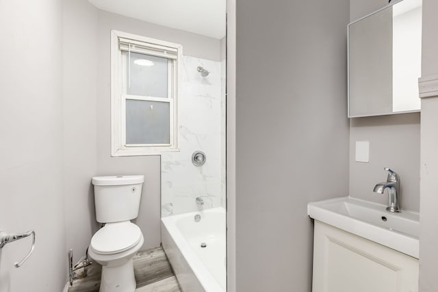 full bathroom with vanity, hardwood / wood-style flooring, tiled shower / bath, and toilet