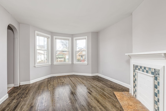 unfurnished living room with dark wood-type flooring and a tiled fireplace