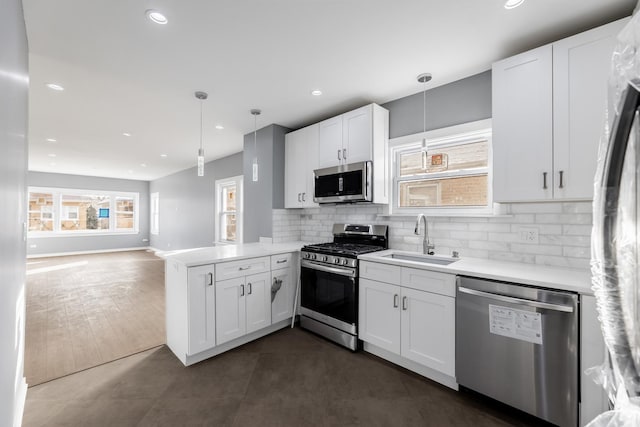 kitchen with kitchen peninsula, appliances with stainless steel finishes, decorative light fixtures, and sink