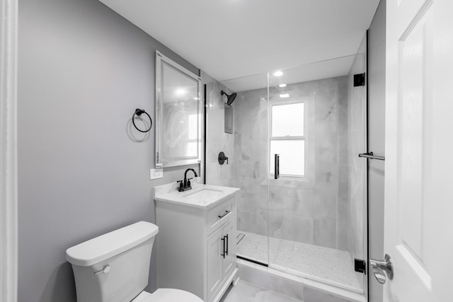 bathroom featuring vanity, toilet, and a shower with shower door