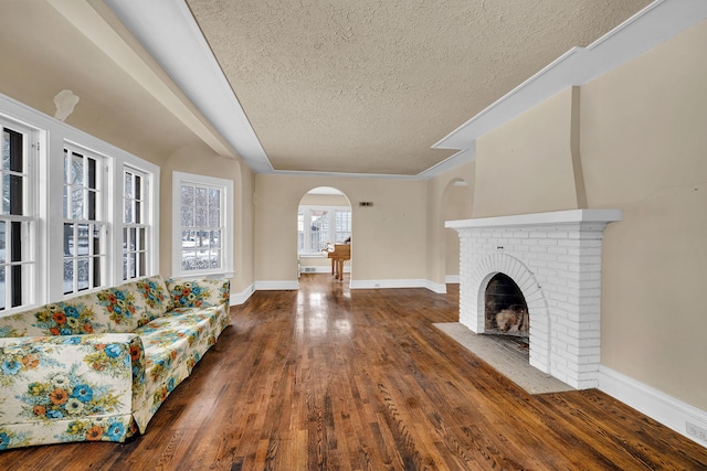 unfurnished living room featuring dark hardwood / wood-style flooring, a textured ceiling, and a brick fireplace