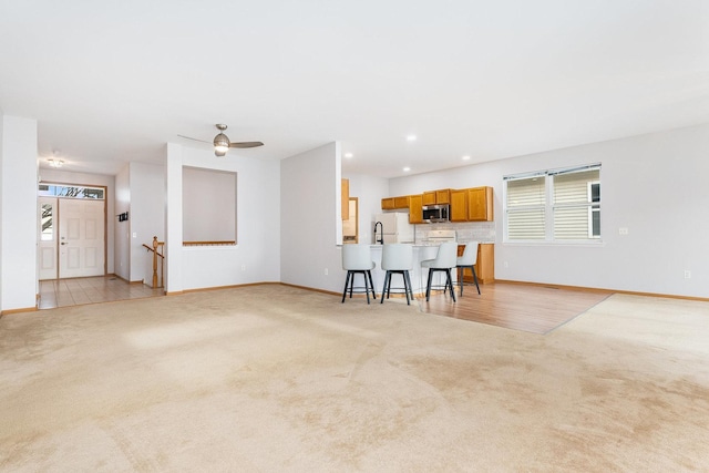 unfurnished living room featuring ceiling fan and light colored carpet